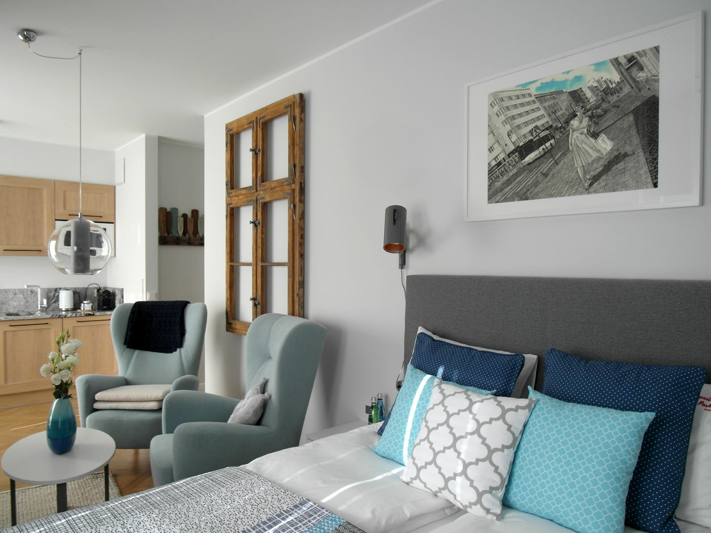 Sea 7 design, Sea window apartment, a view of the bedroom with blue armchairs and a decorative wooden window frame.
